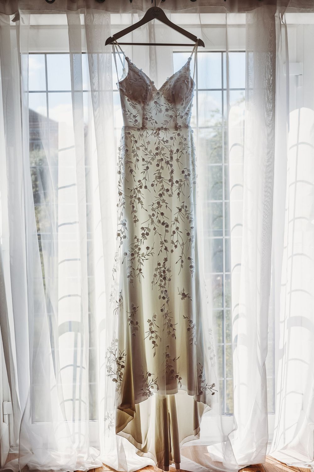 Photo of wedding dress hanging up in the window with back light. Captured by Dorset wedding photographer.