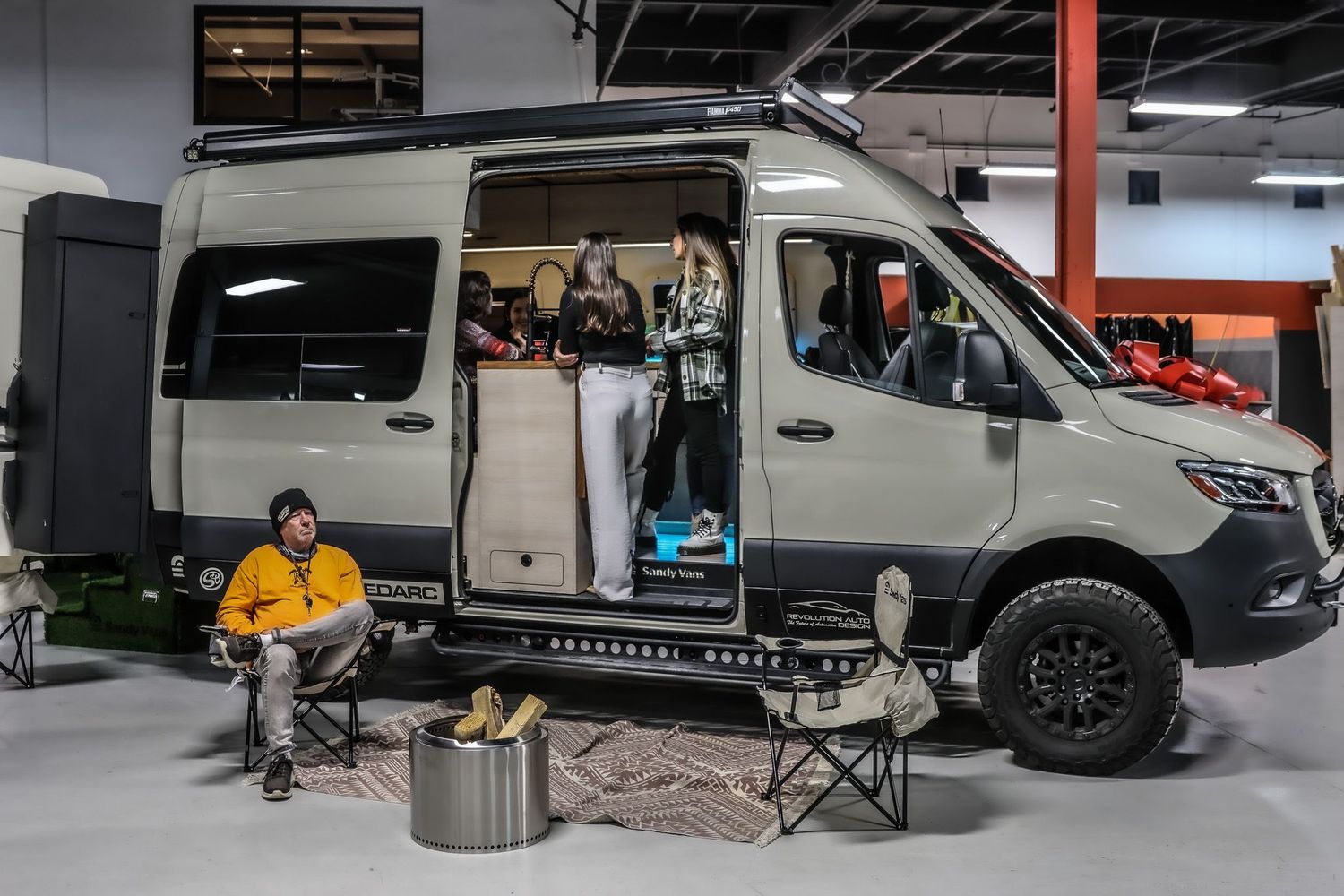 Sandy Vans custom Mercedes Sprinter camper conversion commercial photography highlighting indoor kitchen and camping setup.