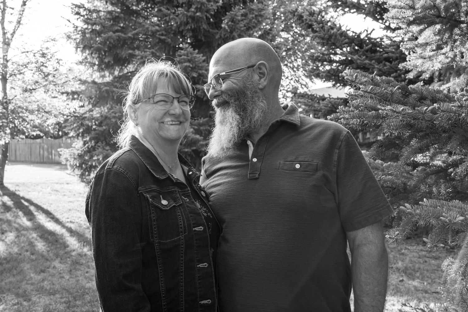 a black and white photo showing a couple with trees behind.