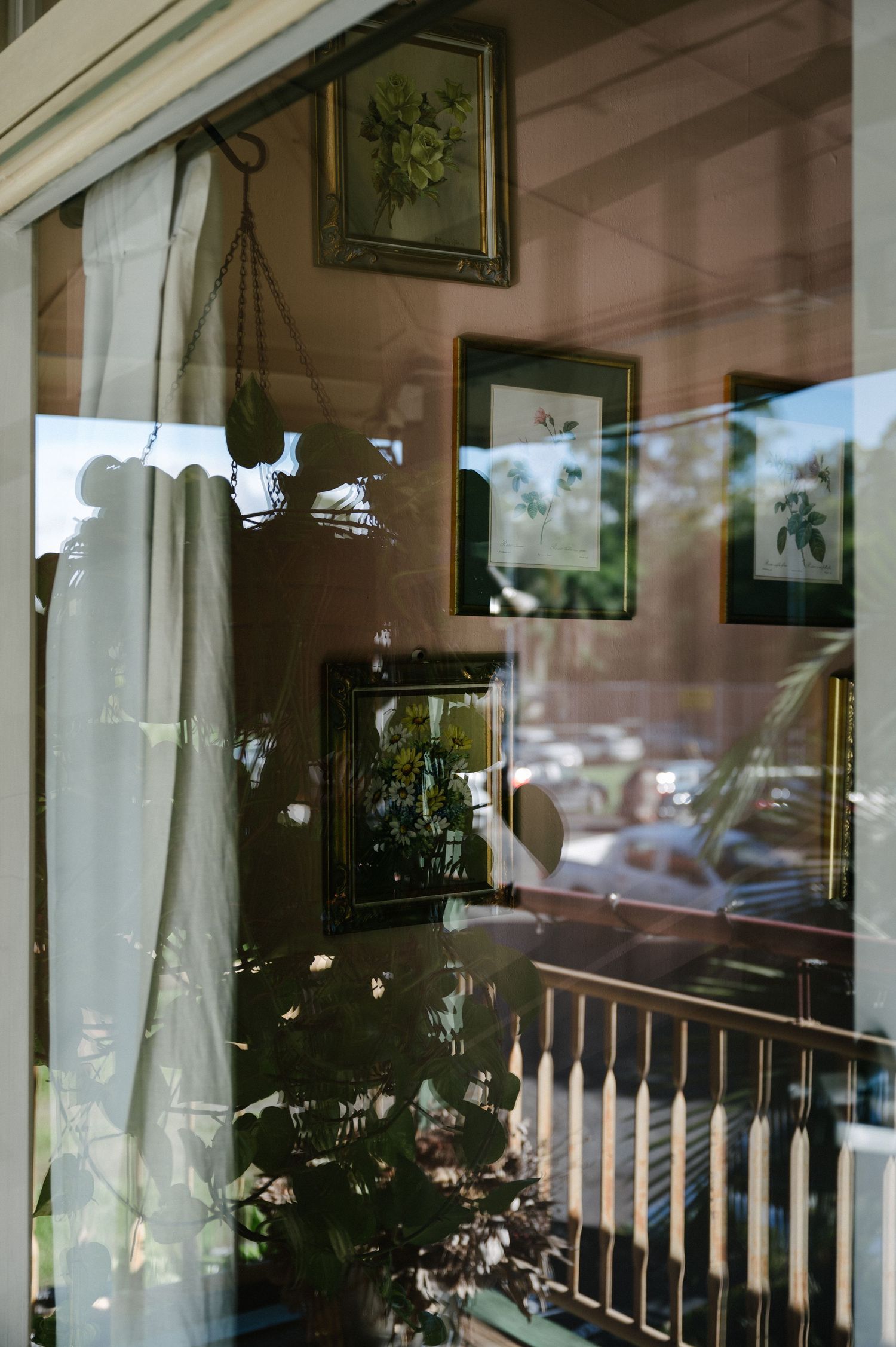 Sunlit room interior with reflections in window glass showing curtains and home decor against soft lighting.