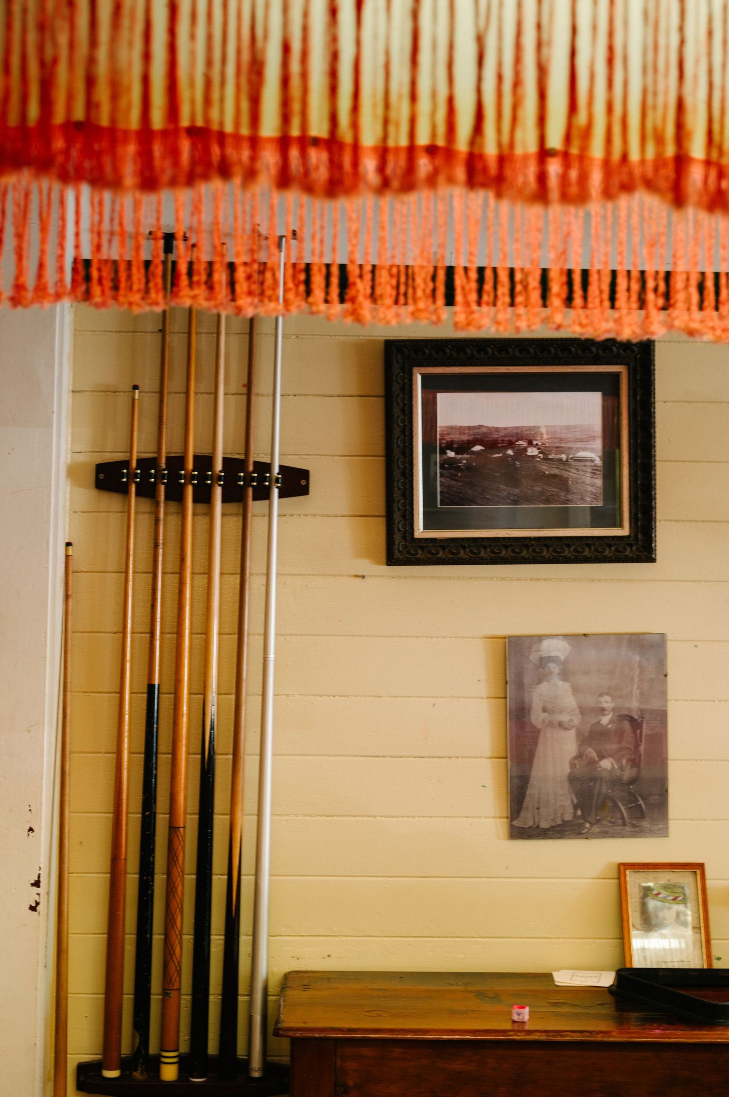 Vintage black and white photographs hang on a wall beneath decorative red valances and curtains.