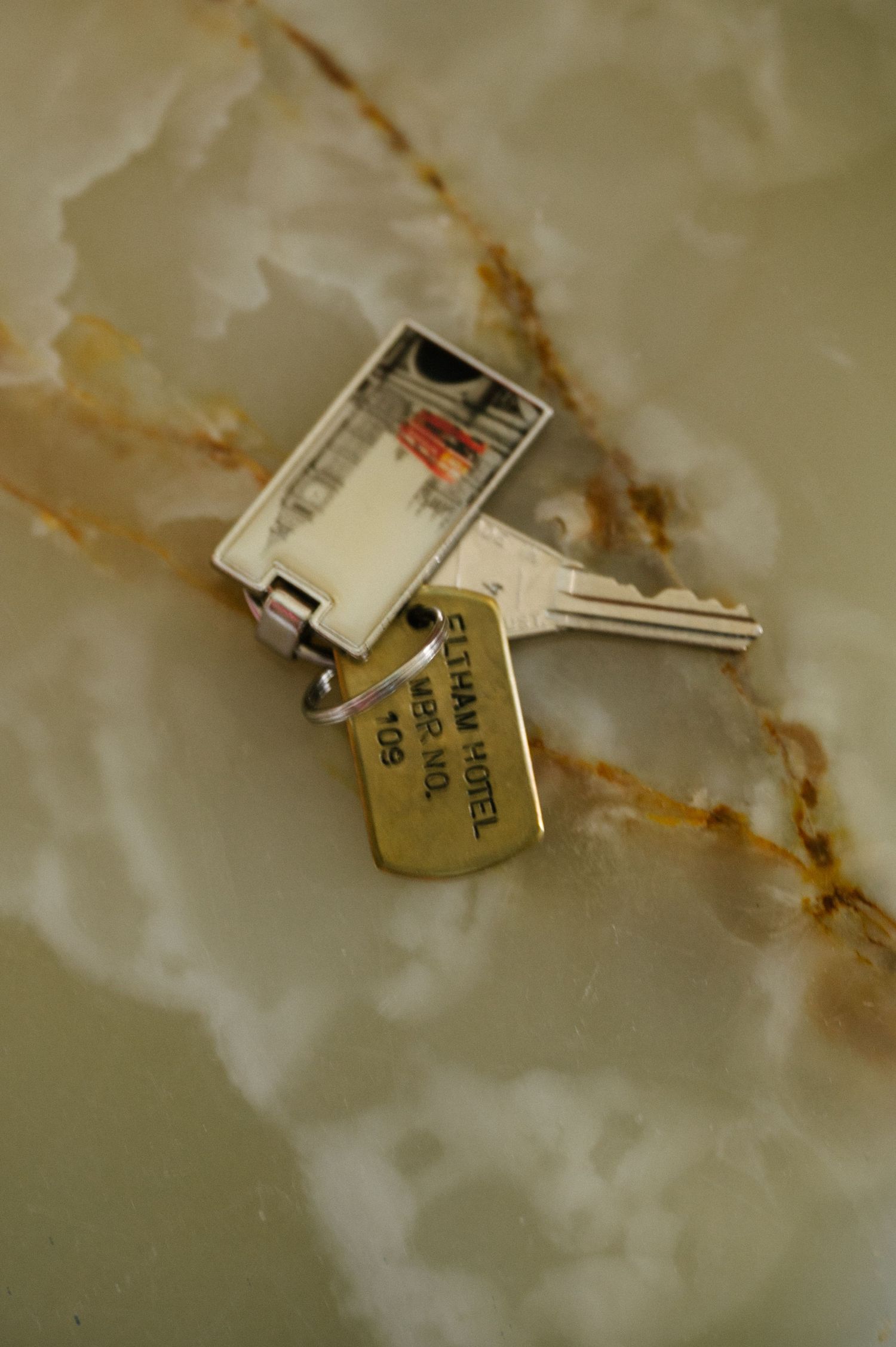 A set of brass keys resting on a white marble or stone surface with brown veining patterns.