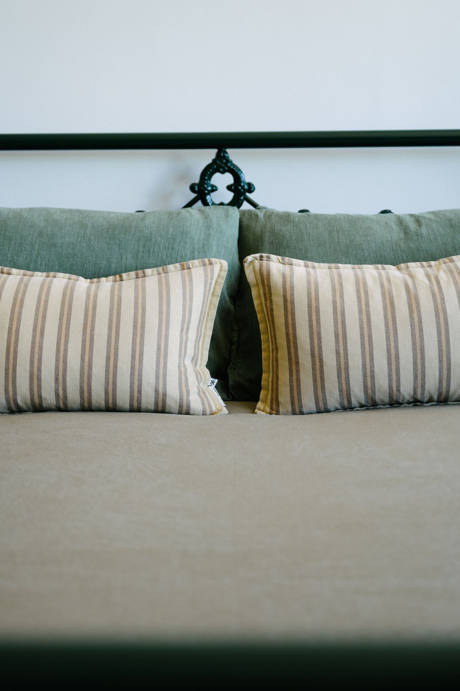 Three striped decorative pillows lined up against a gray cushioned surface cast in moody lighting.