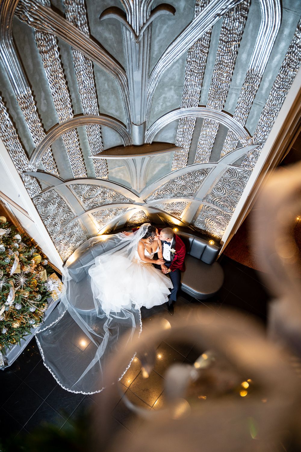 Latino bride and groom kissing by large silver wall in Chataeu Briand Caterers