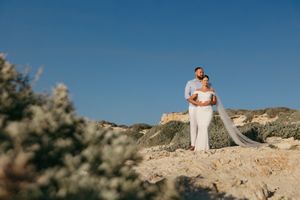 A couple shares an intimate moment atop a scenic desert cliff during their outdoor photo session at sunset.