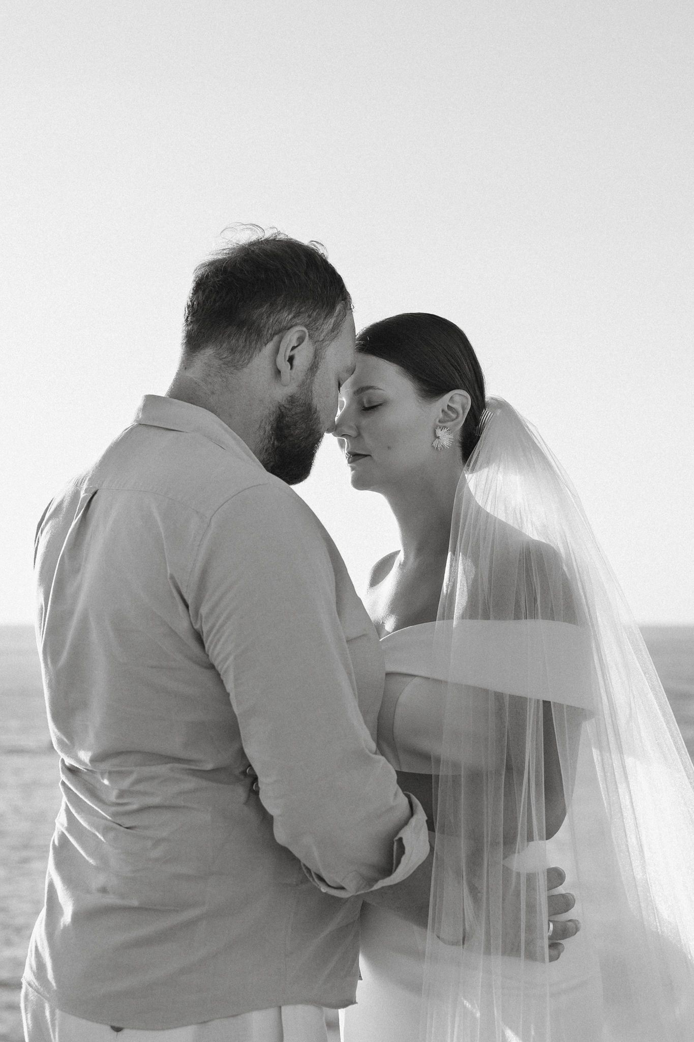 A romantic black and white photo series showing a couple in wedding attire embracing by the Cyprus sea.