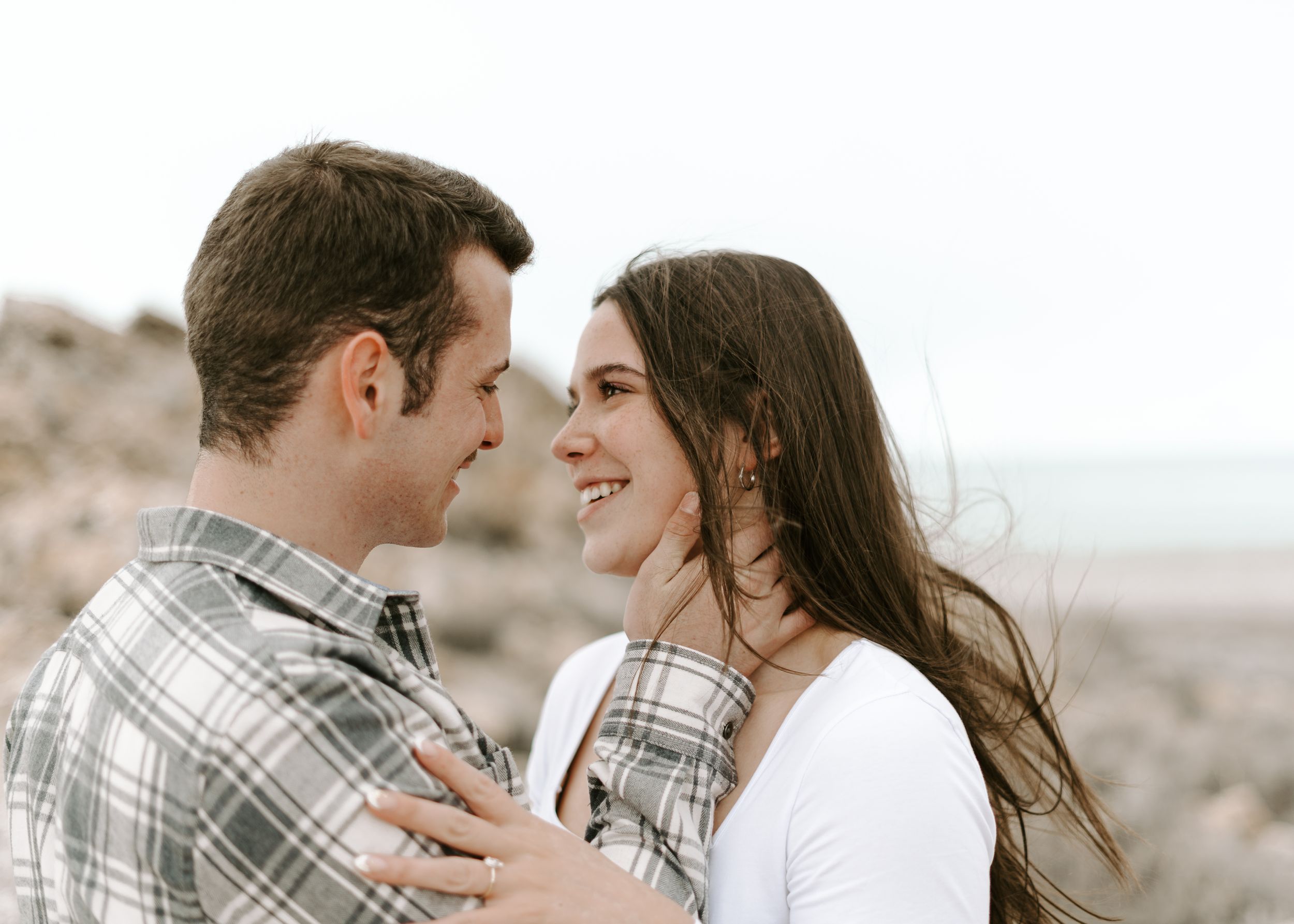 A couple laughs together during an intimate moment on a rocky terrain.