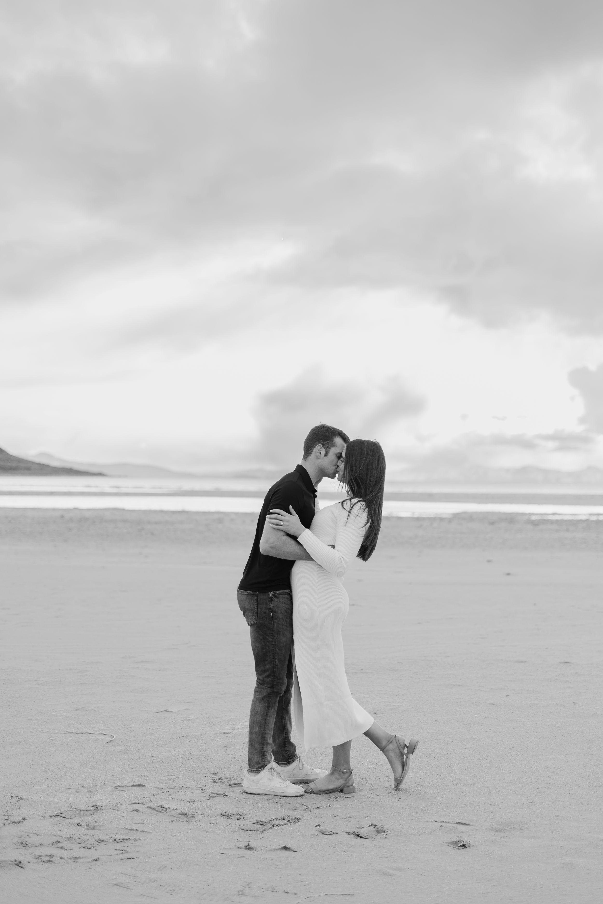 Black and white photo of couple embracing on a misty beach.