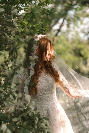 Ethereal bridal portrait series in a sunlit garden with flowing white lace dress and floral details.