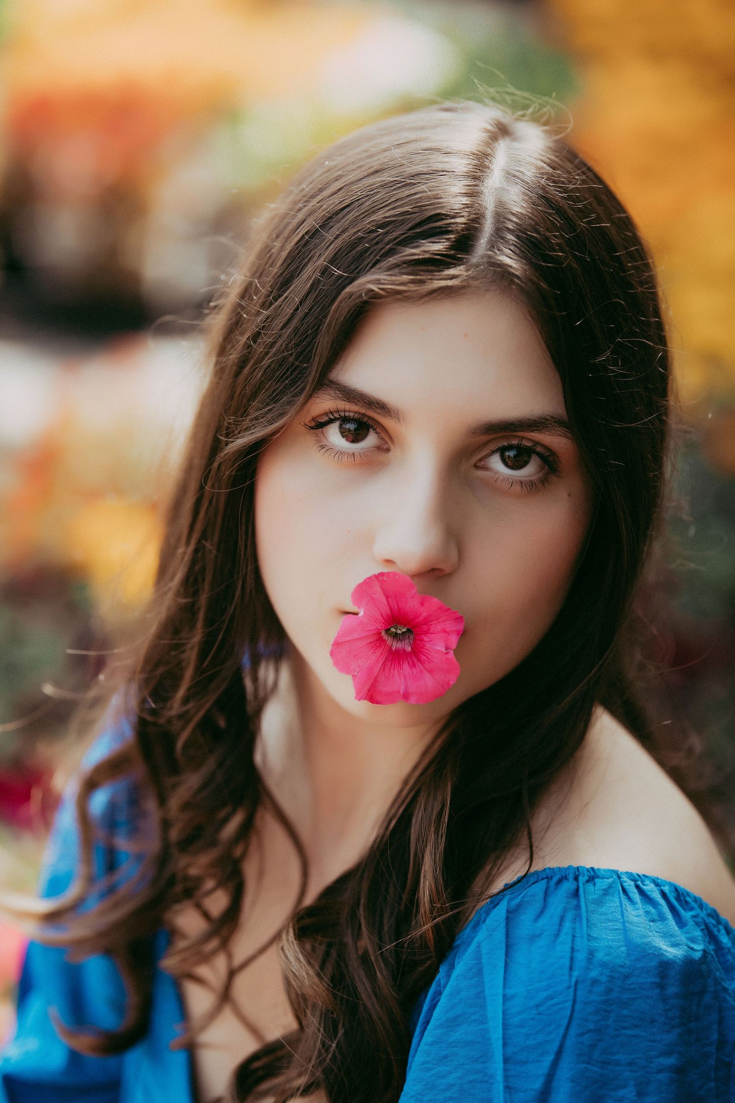 A creative portrait features a bright pink flower placed against autumn colors.