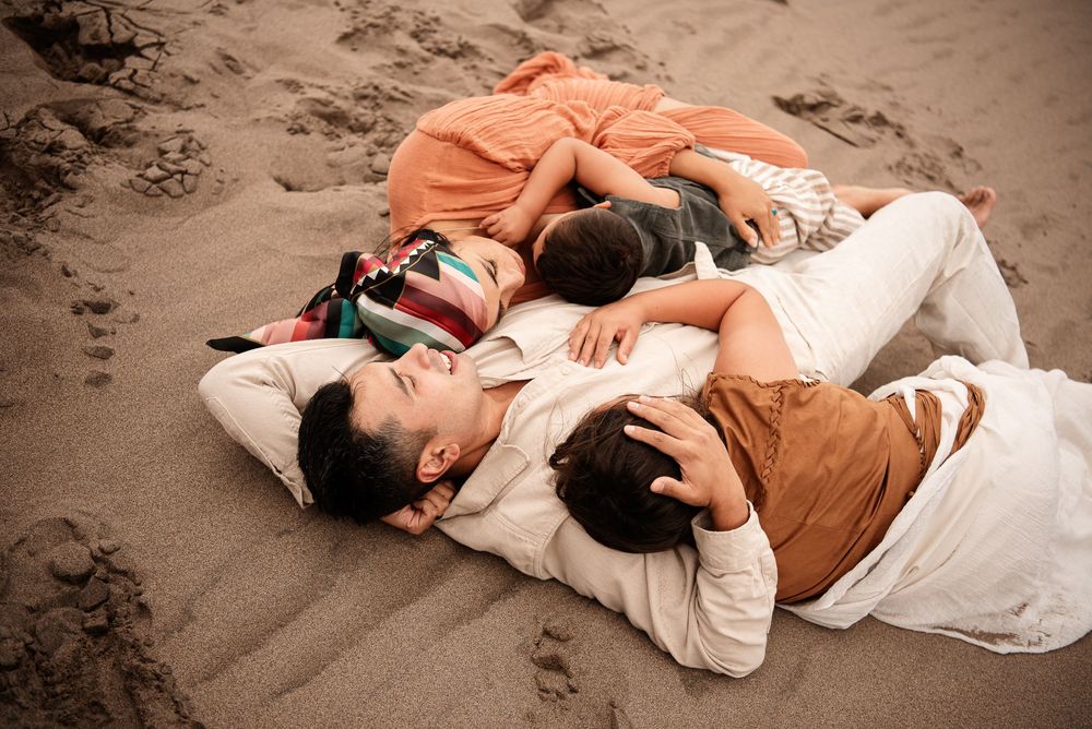 family embracing on the sand laying down at the Great Sand Dunes Colorado