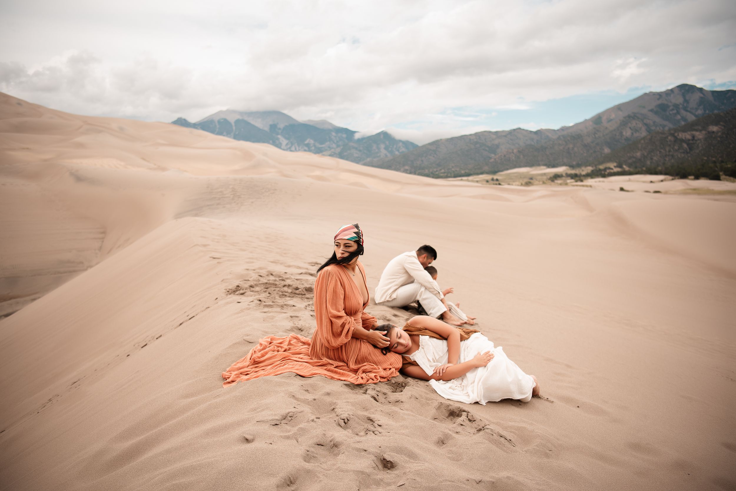 family embracing onthe sand dunes with a landscape view of the mountains in the back