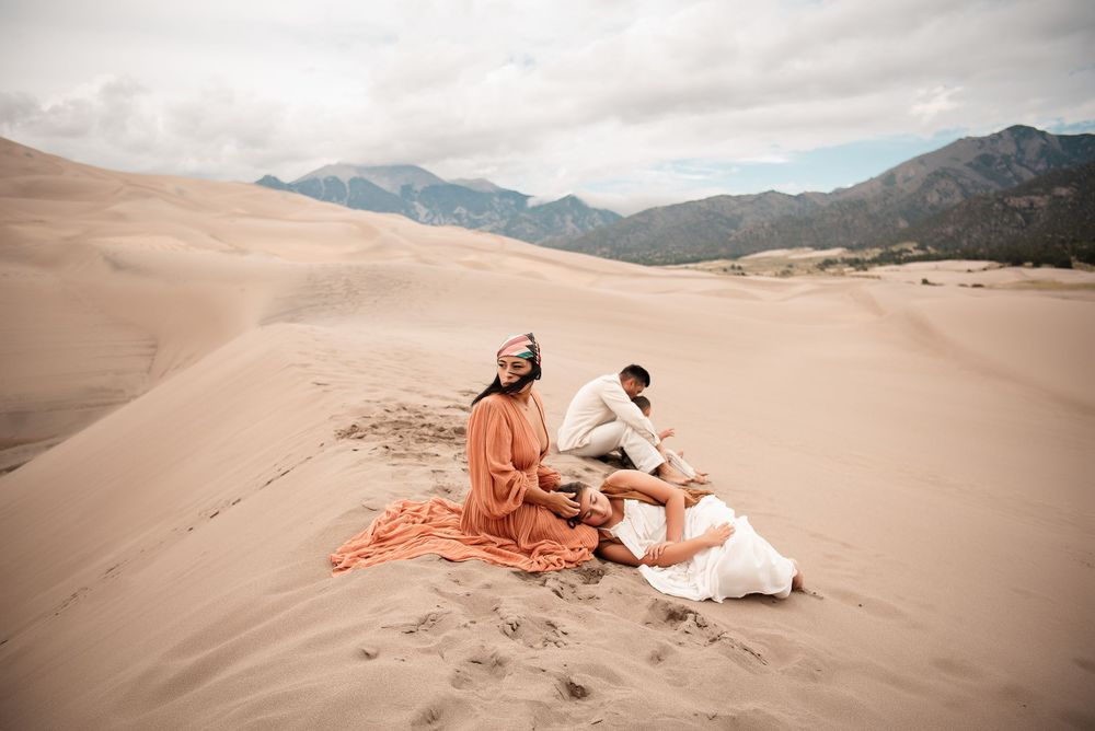 family embracing onthe sand dunes with a landscape view of the mountains in the back