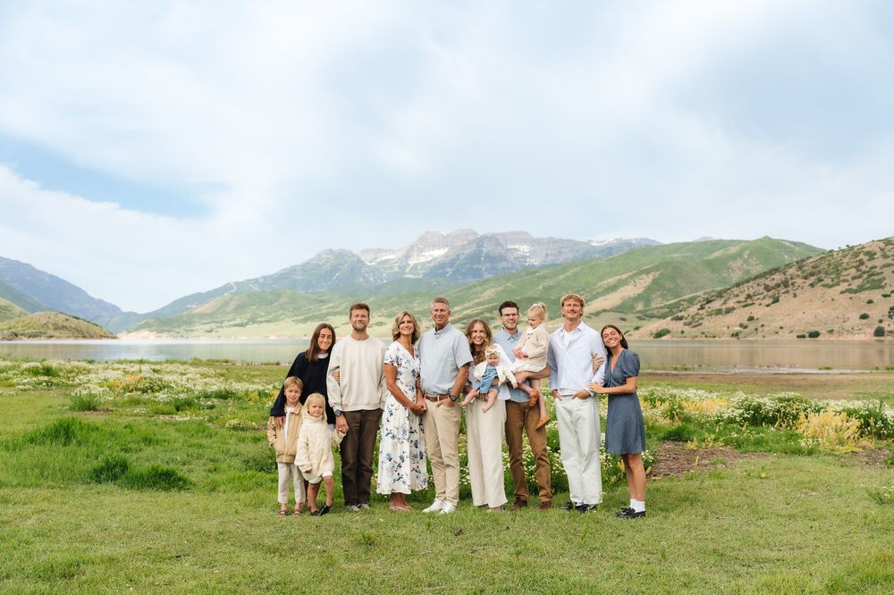 A group enjoying a sunny day in a mountain meadow filled with wildflowers and rolling hills.