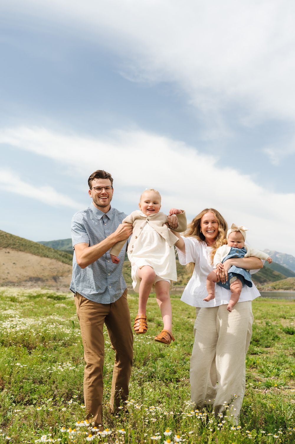 Family playing together in a scenic mountain field with white wildflowers blooming.