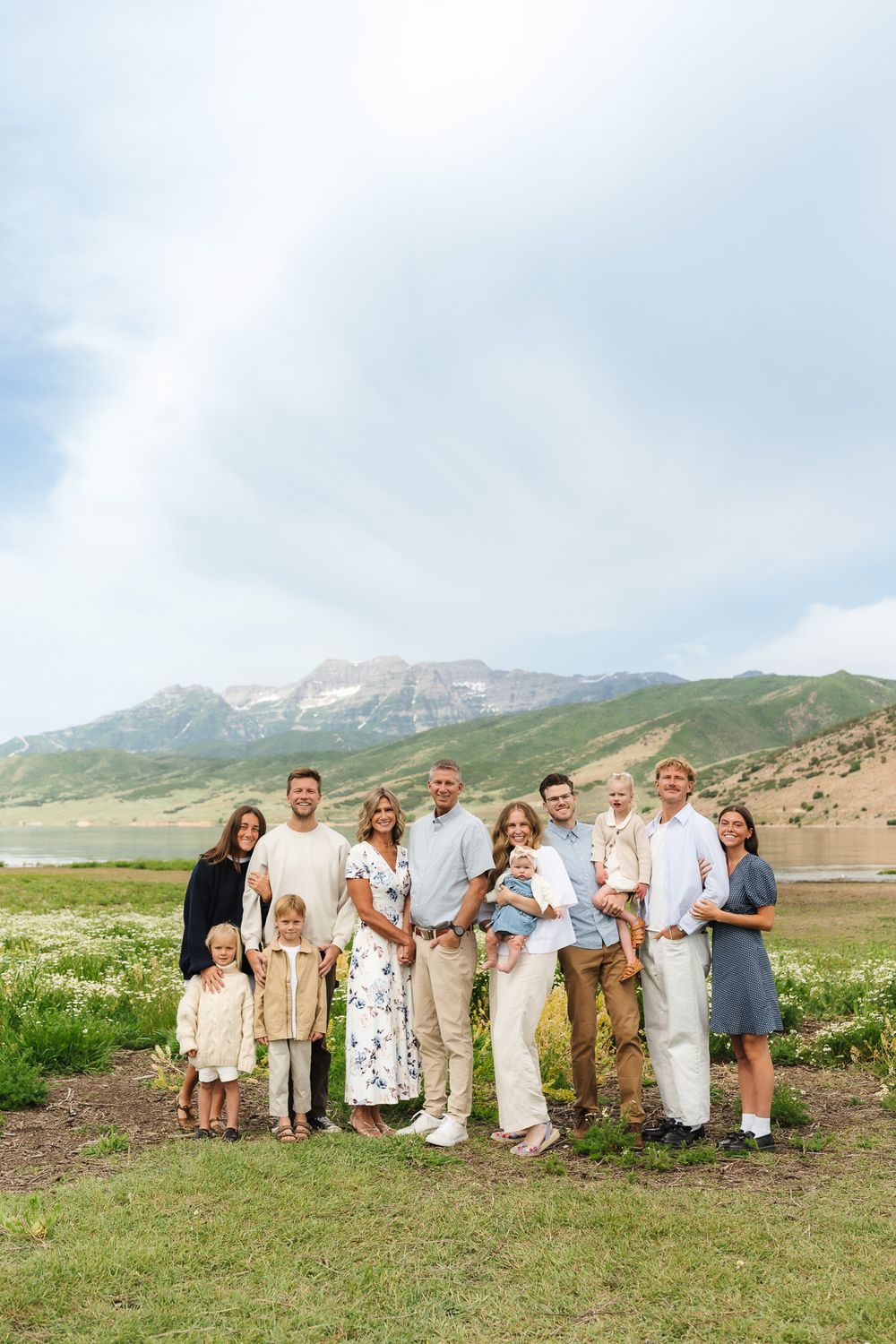 Extended family gathering posed together in a beautiful mountain landscape with green hills.
