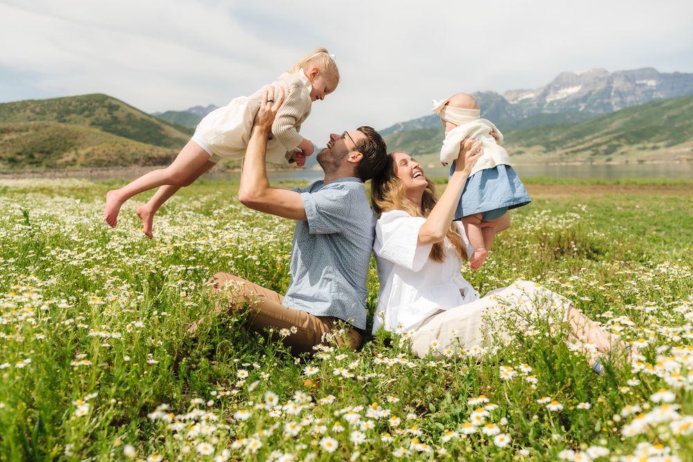 Playful moments captured in a wildflower meadow with mountains in the background.