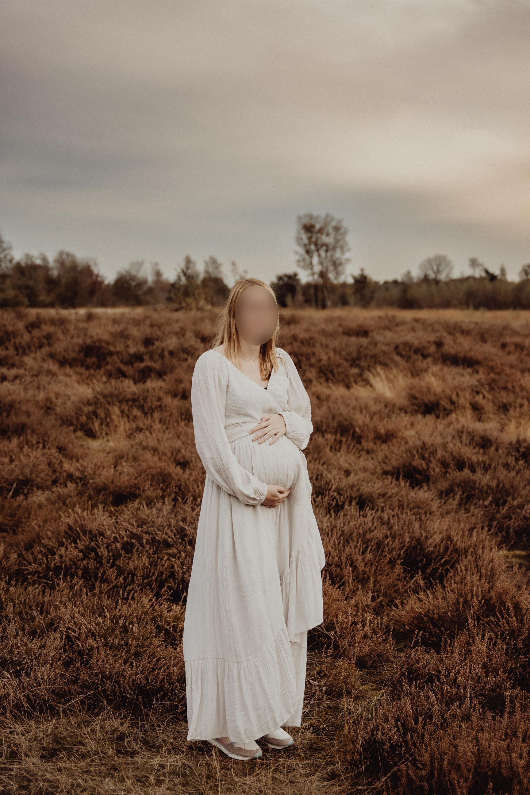 A flowing white dress catches the golden light in a rustic field during sunset.