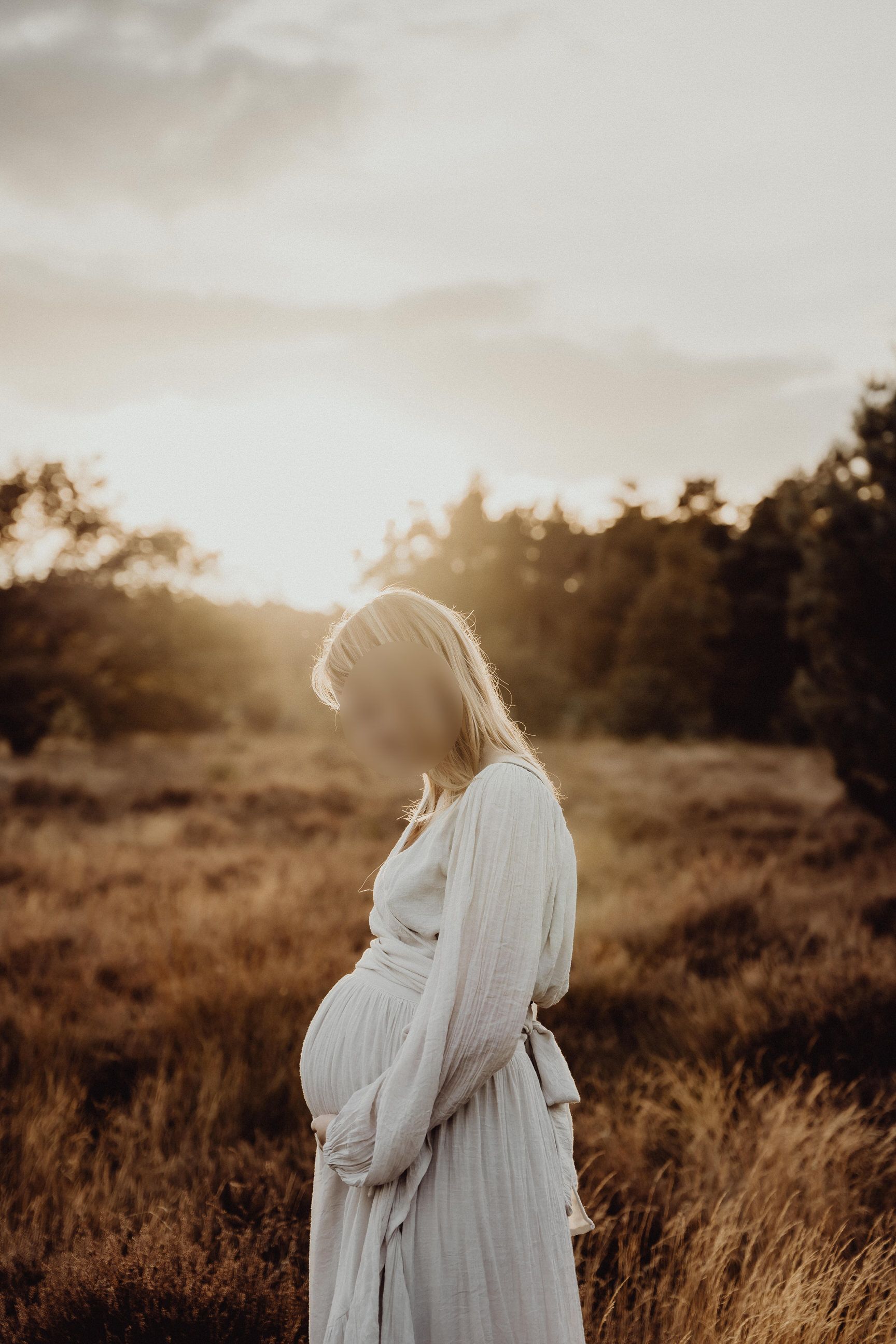 A white dress silhouetted against the setting sun in a golden field of tall grass.