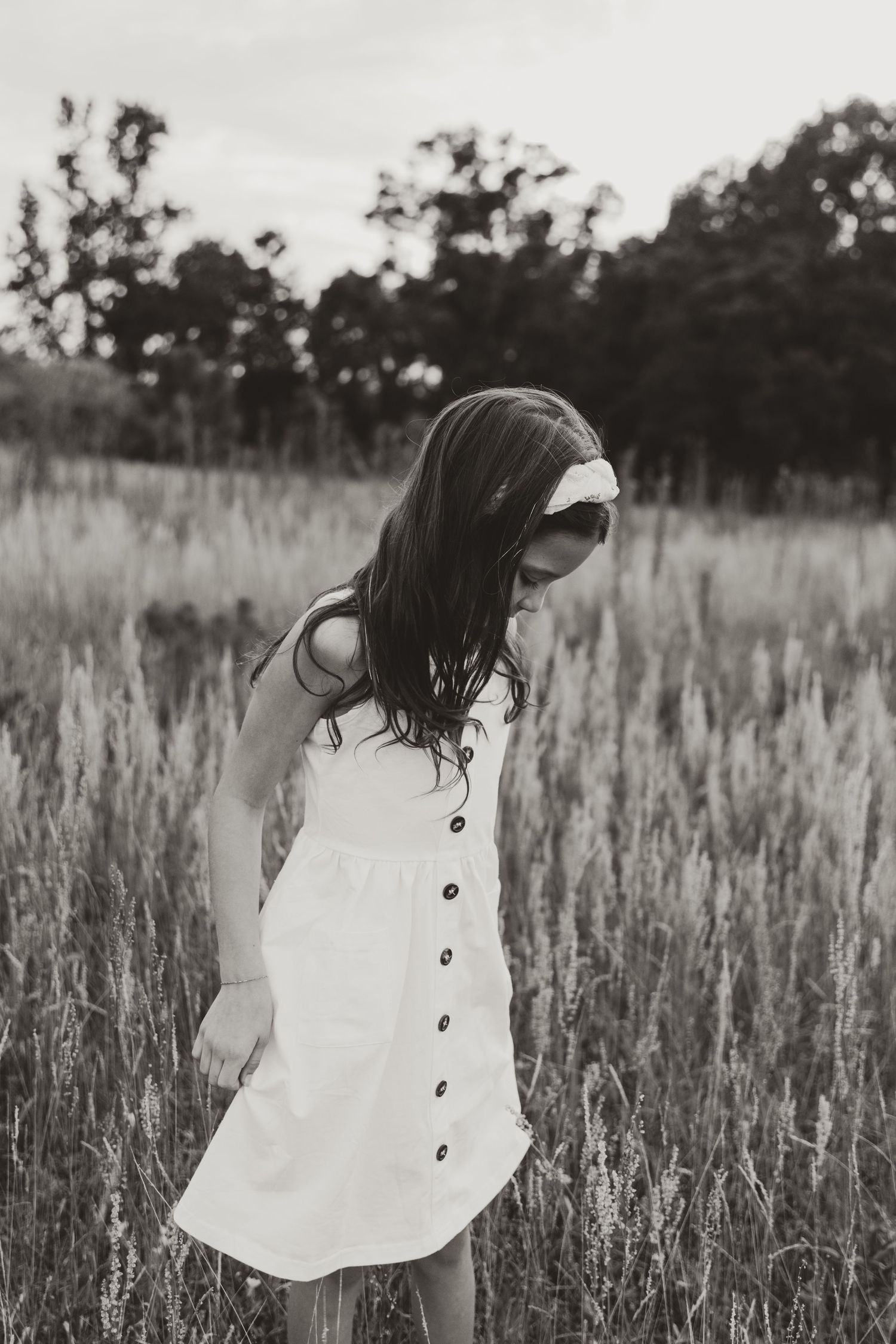 A series of four black and white images showing someone in a white dress moving through a tall grass field.
