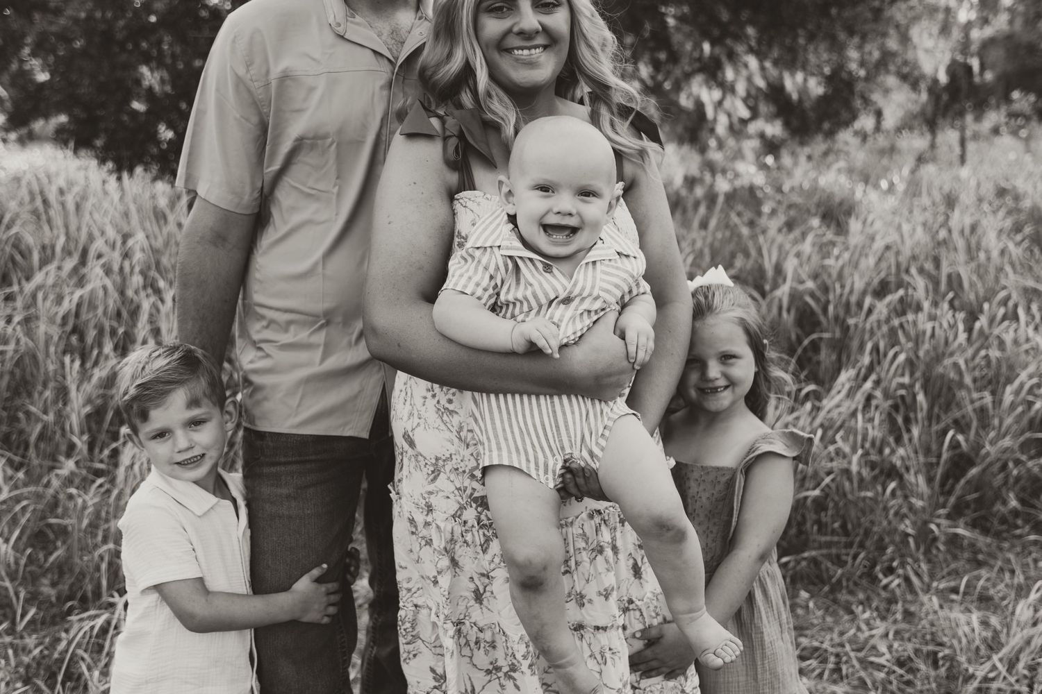 A black and white photo series shows a heartwarming family photoshoot outdoors with playful moments in nature.