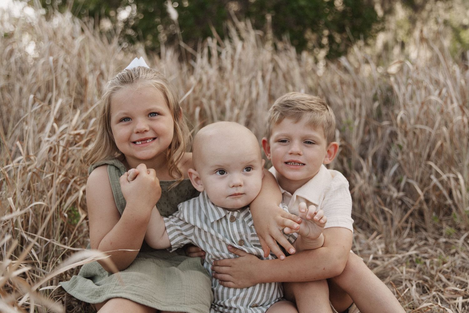 A series of family photos taken outdoors in tall brown grass with siblings hugging and embracing in casual attire.