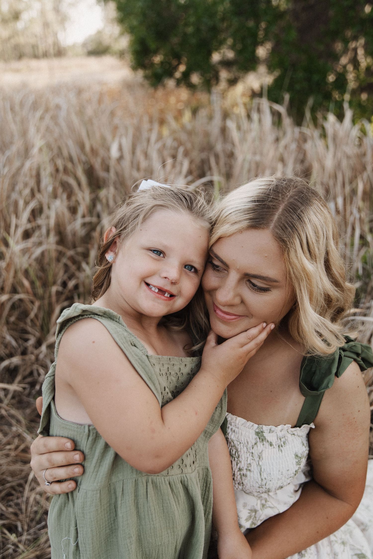 A mother and young child share tender moments outdoors while wearing matching green and white outfits.