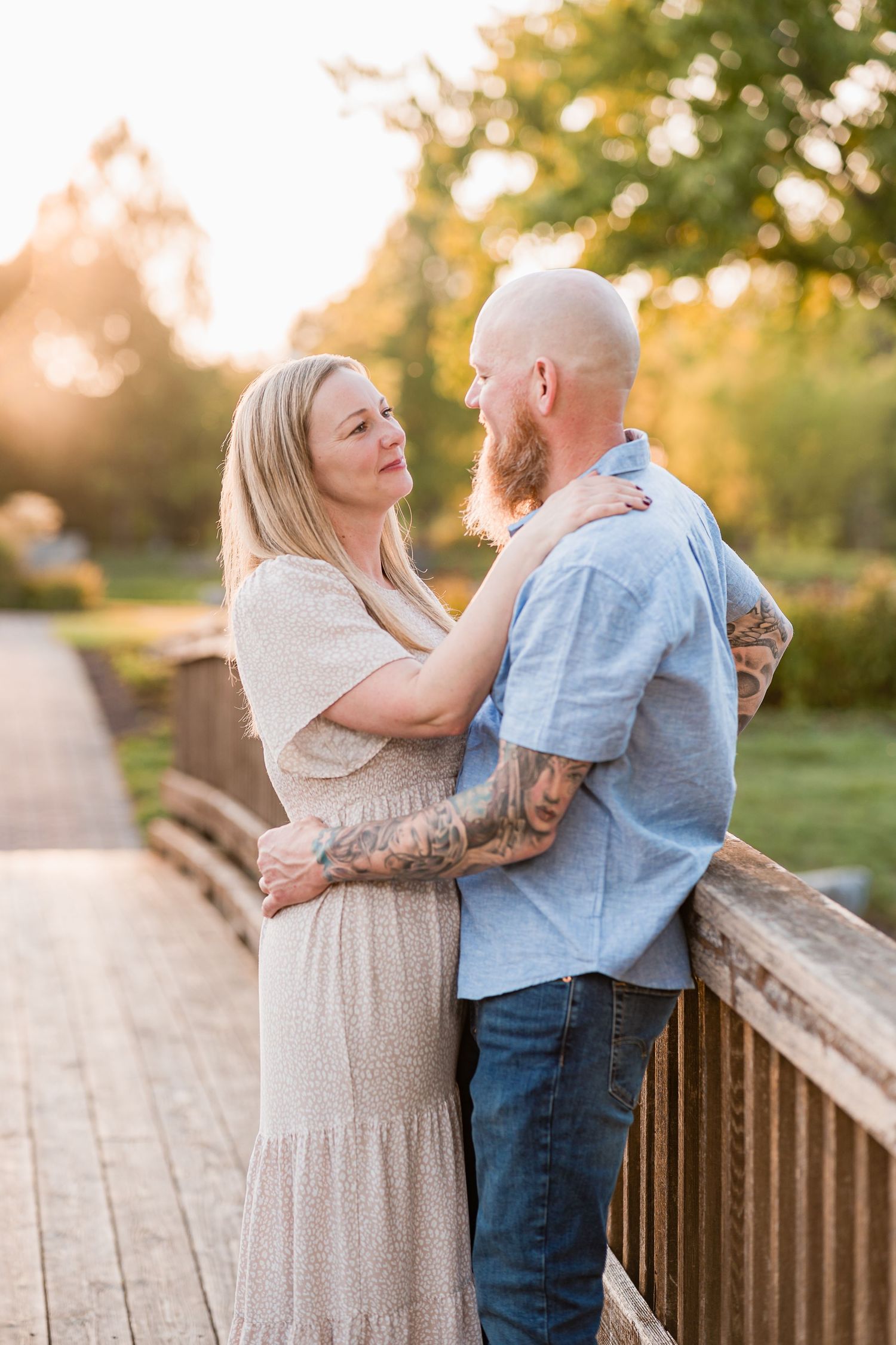 A couple shares a tender romantic moment together on a wooden bridge during golden hour sunset.