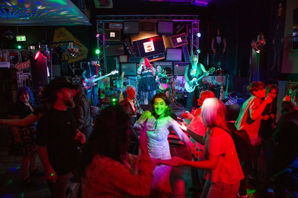 Colorful nightclub scene with dancers under neon lights and live band performing.