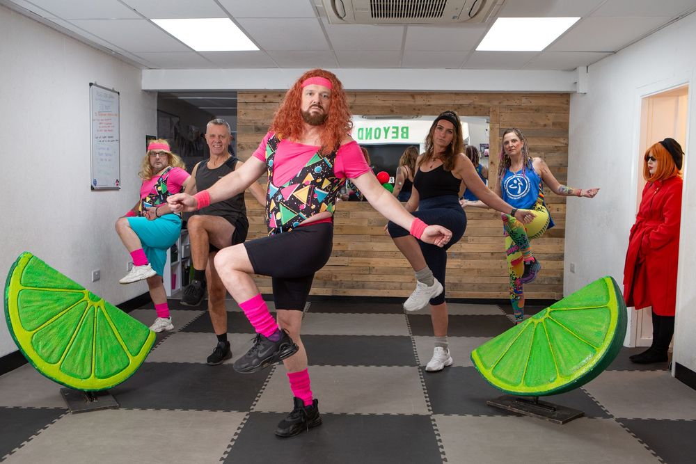 Fitness class participants exercise with lime slice props in a studio setting.
