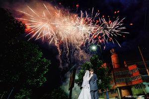 Fireworks light up the night sky with bright red and white bursts during an evening wedding celebration.
