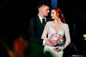 A newlywed couple sharing a romantic moment at night with the bride holding a pink bouquet.