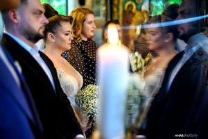 Wedding guests and newlyweds gather during a ceremony with candlelight creating a soft glow in the background.