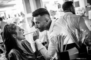 A makeup artist applies cosmetics during a bustling professional beauty session at a salon event.