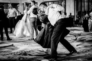 A couple performs a dramatic dance move during a wedding reception in black and white photography.