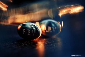 Macro photograph of black P.B.V. pills with dramatic lighting and bokeh effect on dark blue surface.