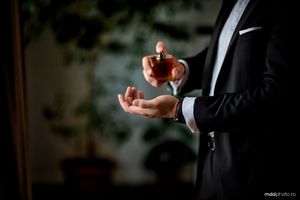 A person in a suit holding a gold wedding ring, captured in dramatic lighting and shallow depth of field.