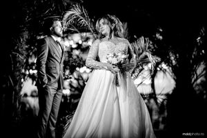 A black and white romantic wedding photograph showing a couple in a garden setting with dreamy bokeh lighting effects.