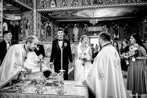 Black and white photo of an Orthodox Christian wedding ceremony taking place inside an ornate church with priests and attendees.