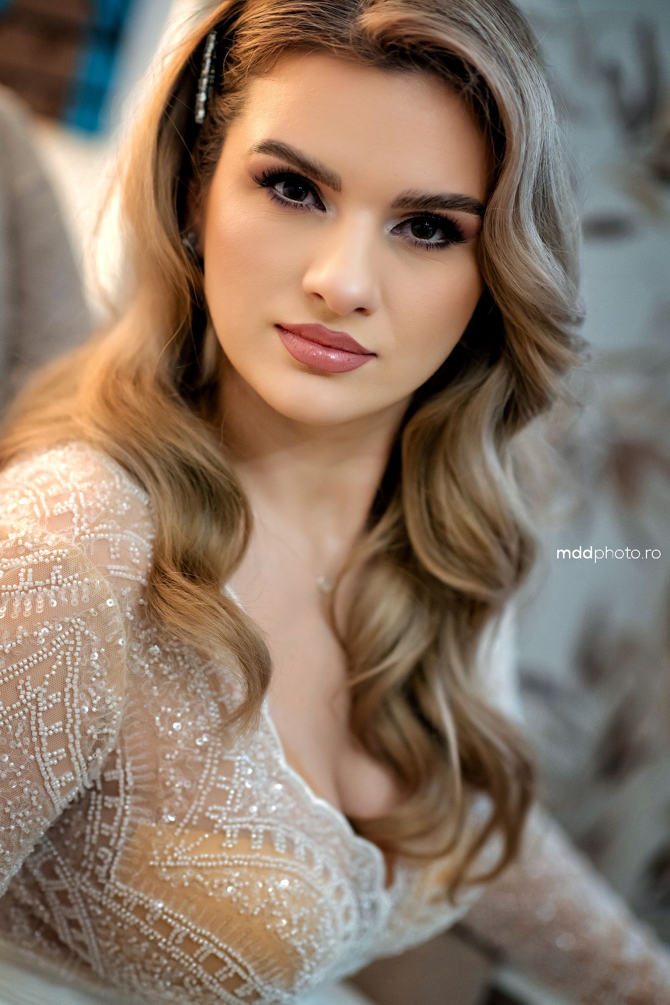 Beautiful bridal portrait featuring soft wavy blonde hair, glamorous makeup and delicate white lace gown.