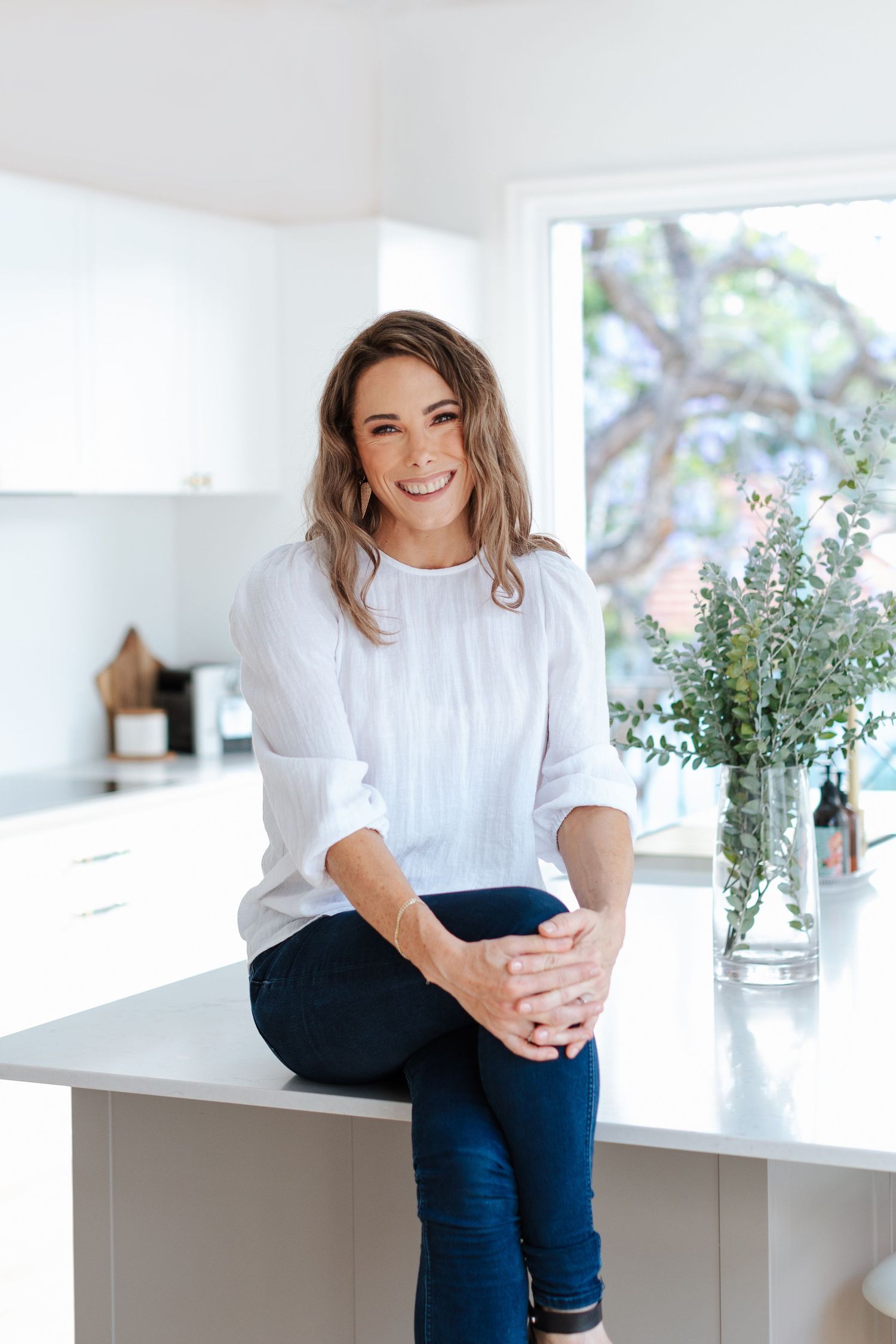 Jo from Joanna Kate Photography in Ashgrove seated in her kitchen in front of her own family portrait