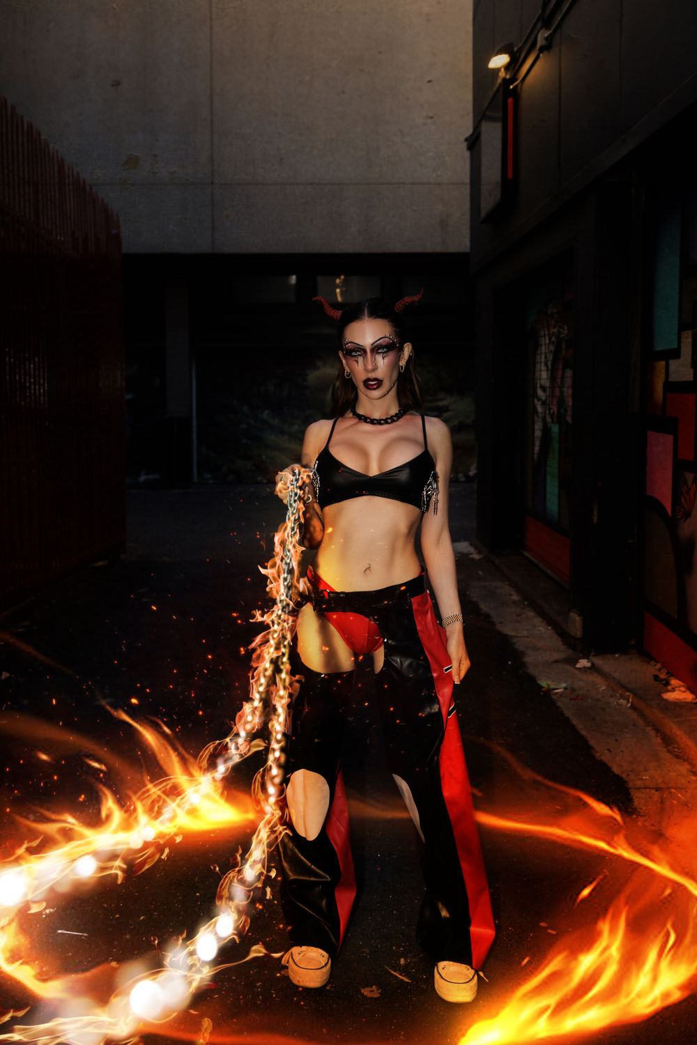 Dramatic photo with flames and a fiery chain in a dark industrial alley setting with moody lighting effects.