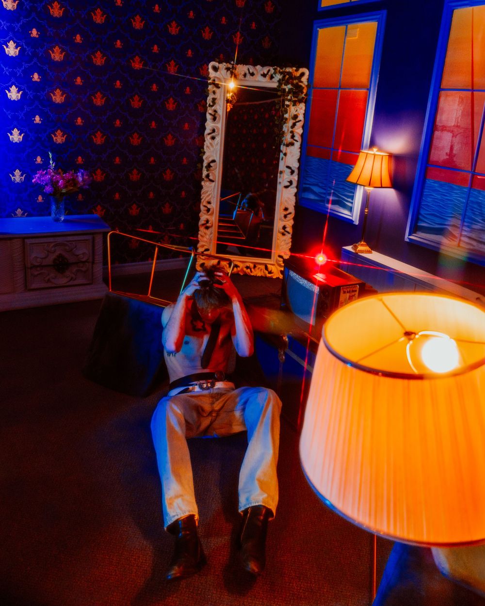 Creative nighttime interior scene with an ornate mirror frame, illuminated by blue and orange lighting with a vintage lampshade.