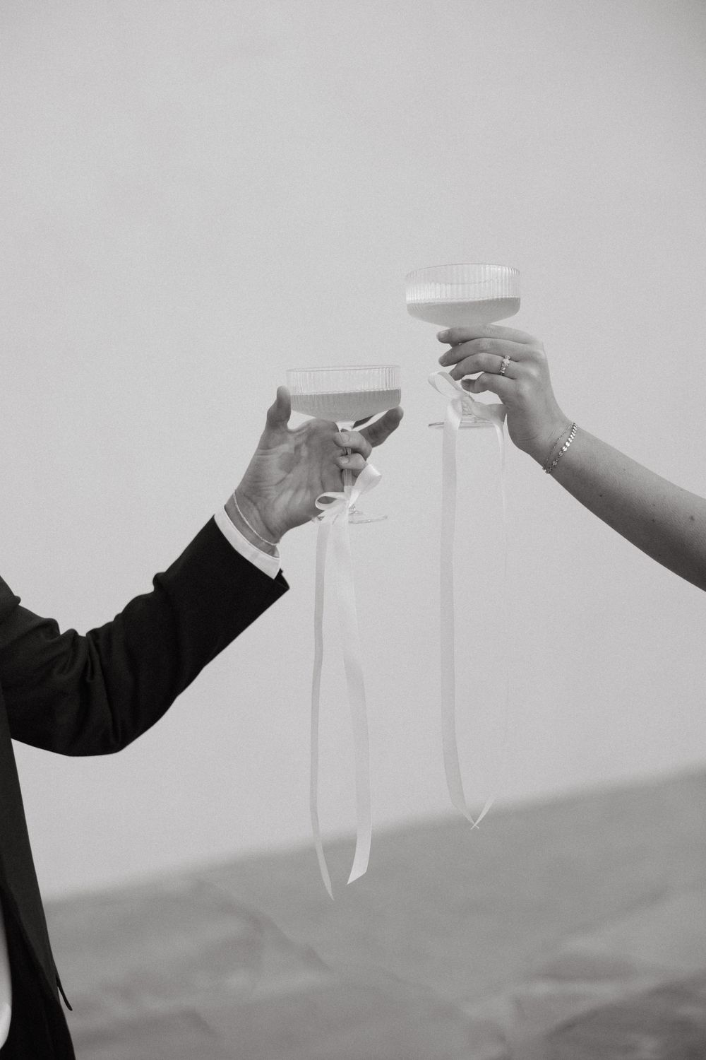 Minimalist black and white series of hands toasting with champagne glasses.