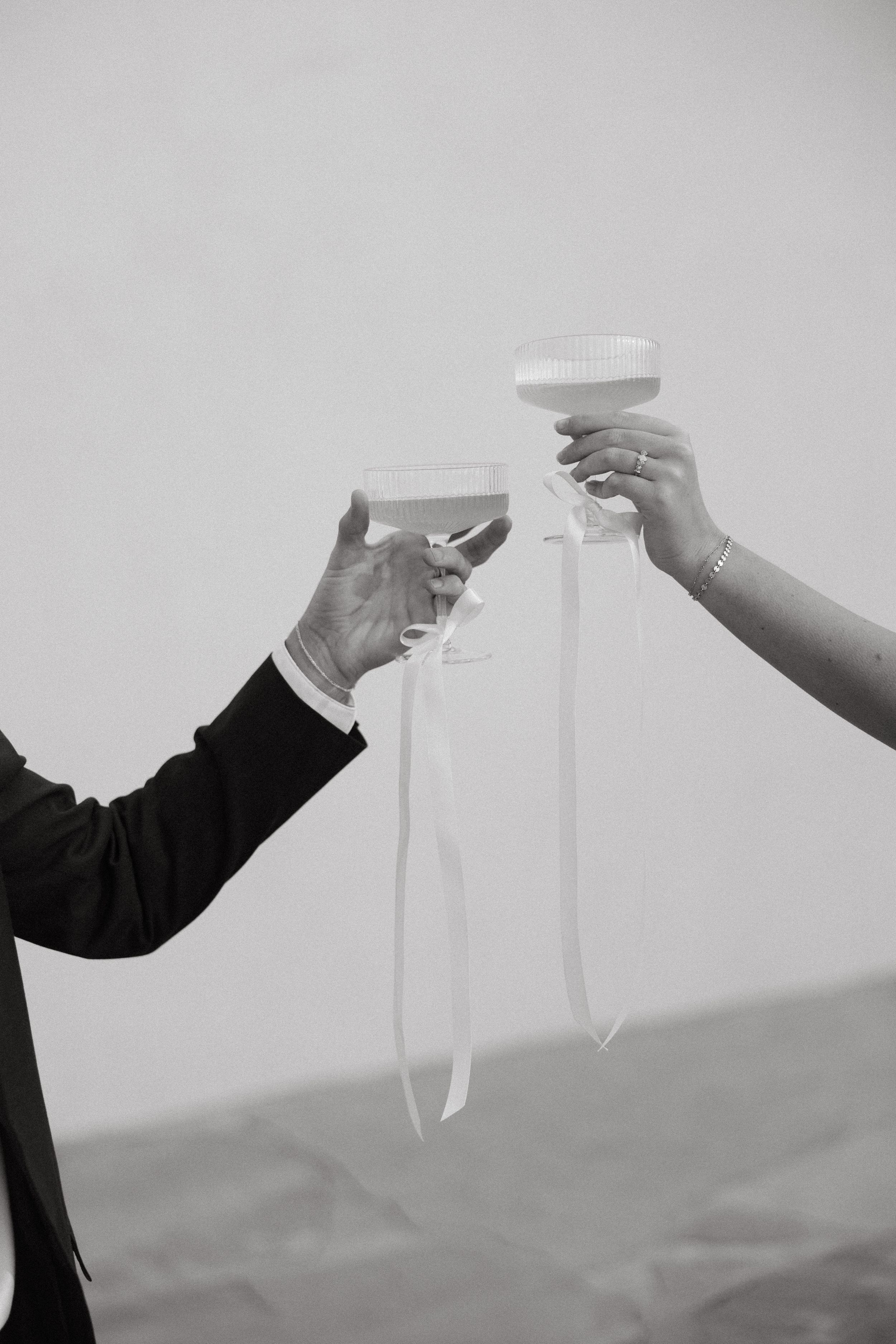 Minimalist black and white series of hands toasting with champagne glasses.