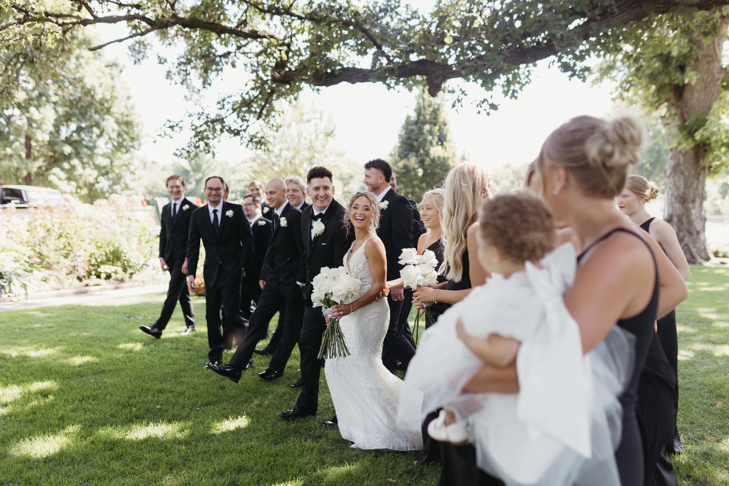 Wedding party poses on wooden deck with scenic natural backdrop.