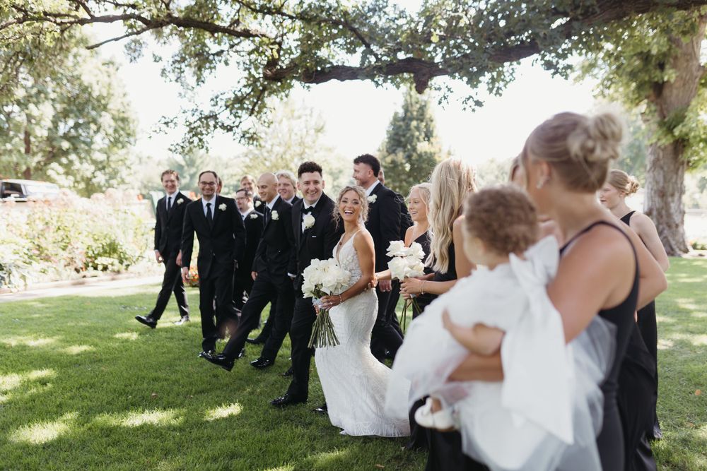 Wedding party poses on wooden deck with scenic natural backdrop.