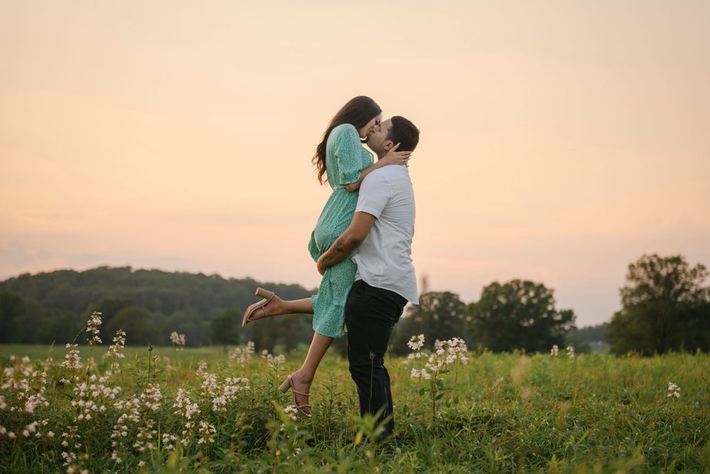 Couple embraces in sunset meadow with wildflowers during romantic golden hour moment in Valley Forge National Historical Park