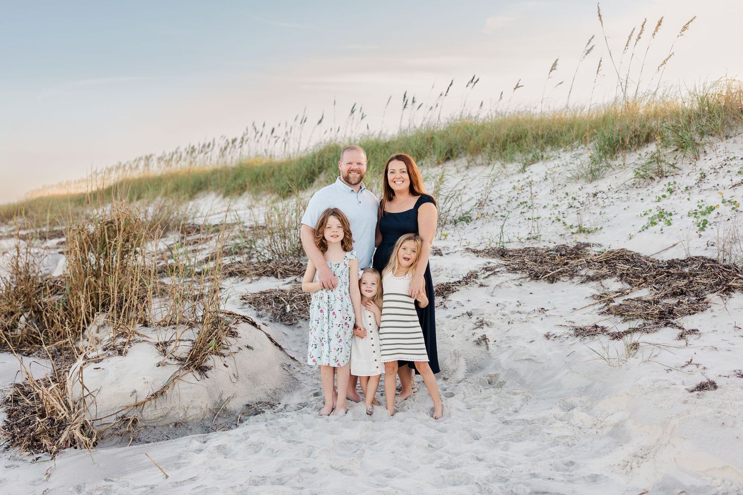 Family portrait session on white sand dunes at the beach during golden hour.