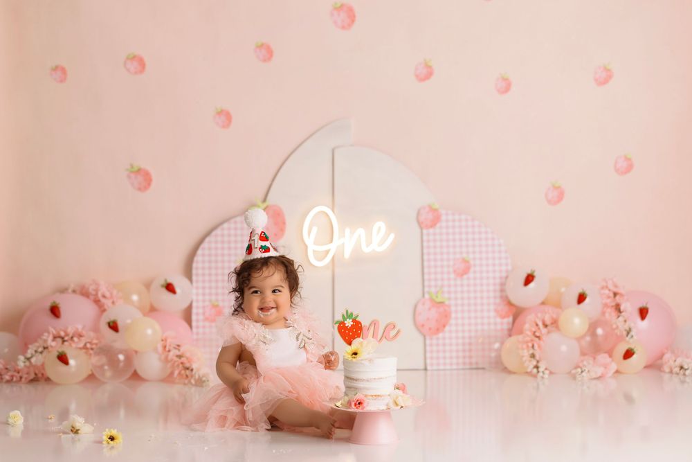 Pink first birthday setup with neon sign and polka dot decorations.